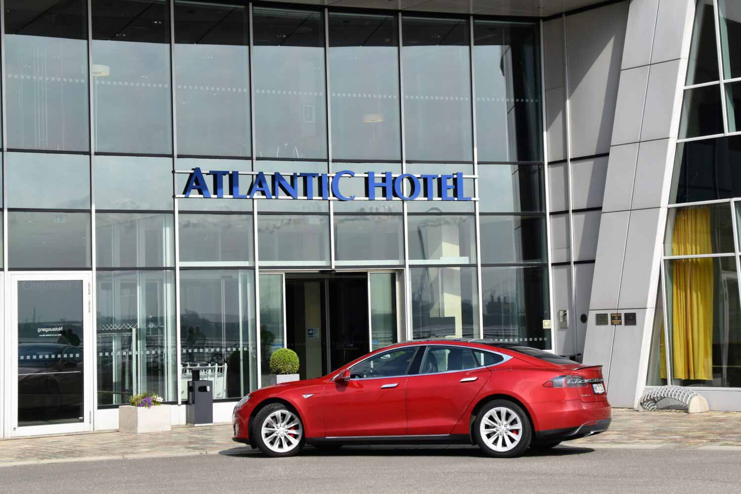 Roter Tesla parkt vor einem Hotel