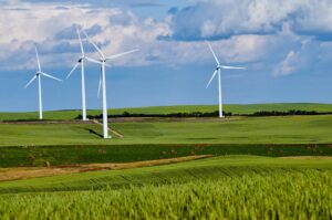Drei Windkraftanlagen auf grünen Feldern.